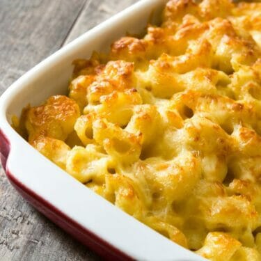 Baked macaroni and cheese in a red and white casserole dish.