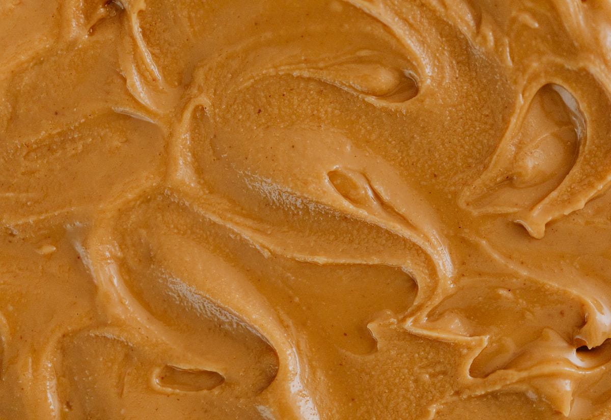 Smooth, creamy peanut butter spread in close-up, showing swirls and texture perfect for homemade peanut butter cups.