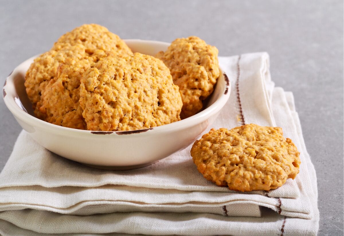 A bowl of golden-brown pumpkin cookies arranged on a cream-colored napkin.