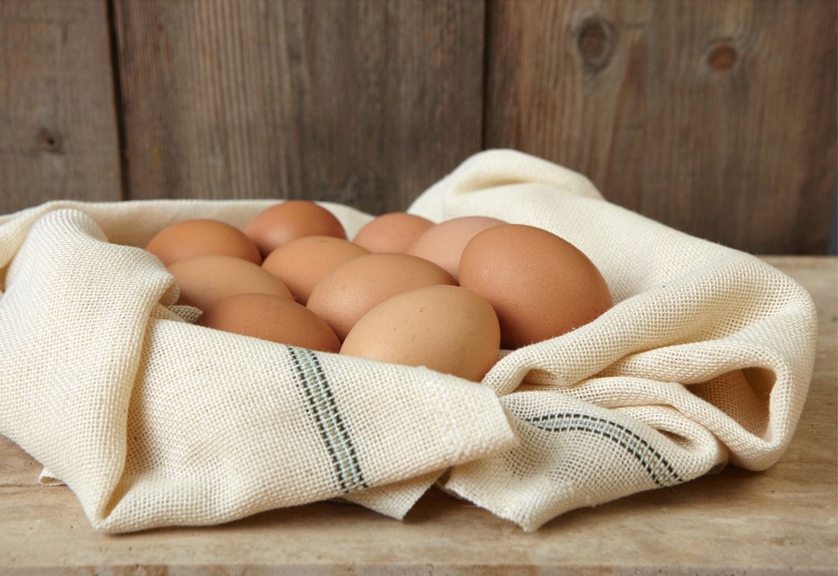 A basket of brown eggs resting on a beige linen cloth.