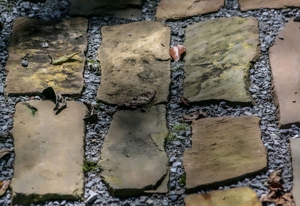 A pathway made of irregularly shaped reused bricks set in gravel.