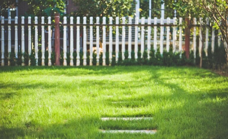 A well-maintained eco-friendly yard with a white upcycled fence in the background.