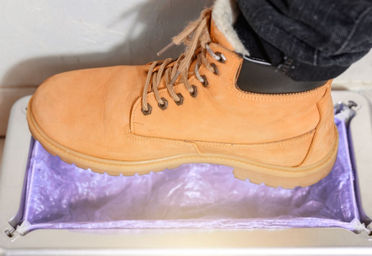 A close-up of a boot being fitted with disposable boot covers for biosecurity purposes.