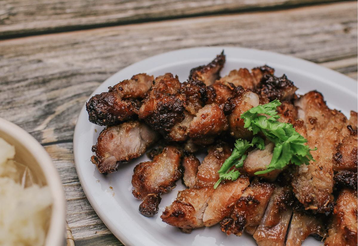 Plate of jerk chicken garnished with fresh parsley on a wooden picnic table.