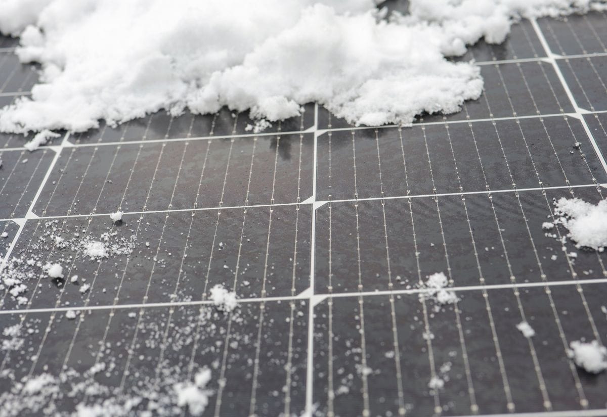 Close-up of snow partially covering solar panels, illustrating their durability and functionality in winter conditions.