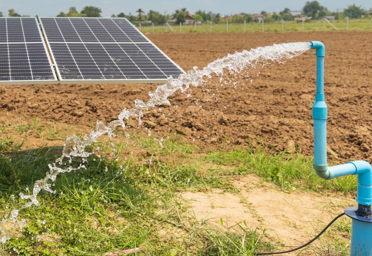 A solar-powered water pump irrigating a field, showcasing solar energy's role in sustainable homesteading.