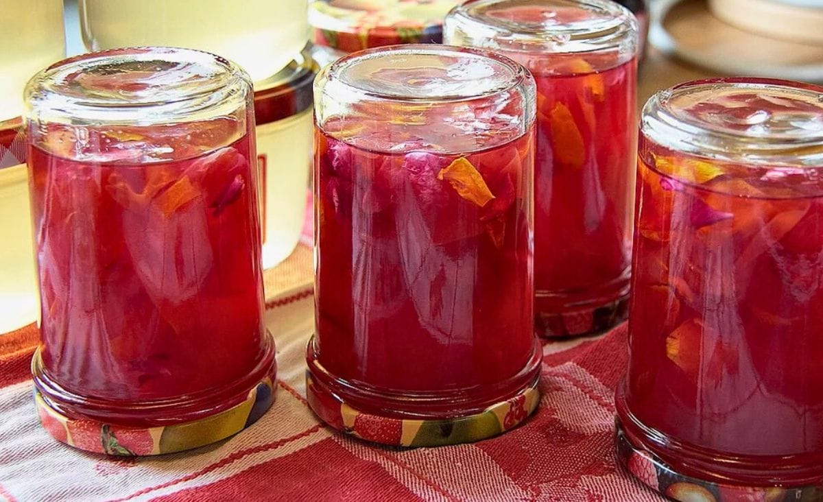 Jars of homemade jelly flipped upside down on a red cloth as part of the inversion canning method.