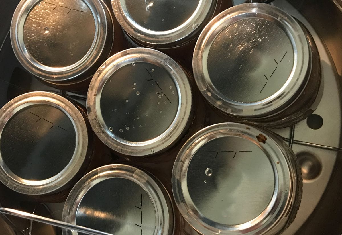 Canning jars submerged in a water bath canner to ensure proper sealing and sterilization.