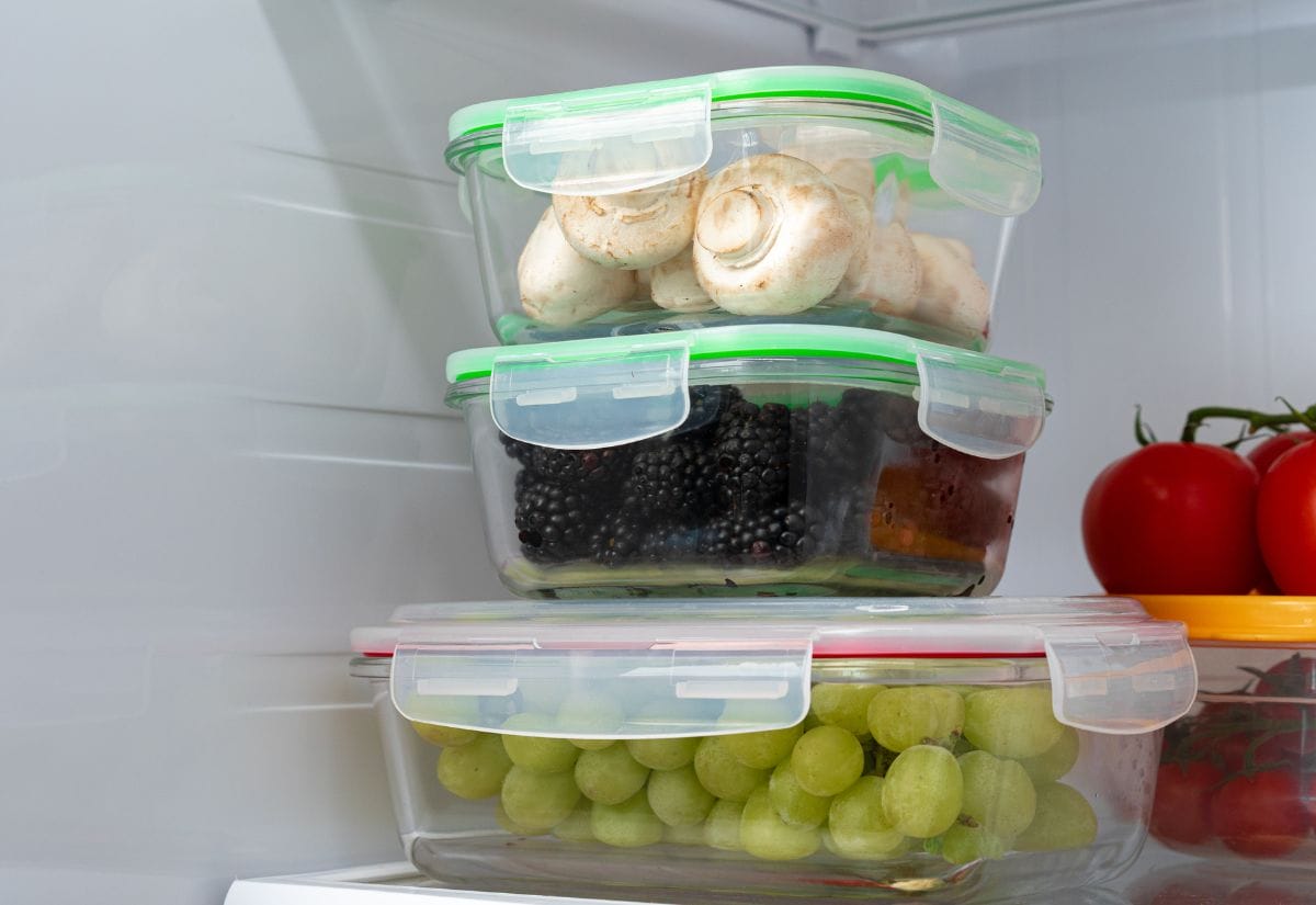 Airtight containers with grapes, mushrooms, and blackberries stored in a refrigerator for optimal freshness.