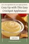 Glass bowl filled with smooth homemade applesauce next to cinnamon sticks, with overlay text "Cozy Up with This Easy Crockpot Applesauce."