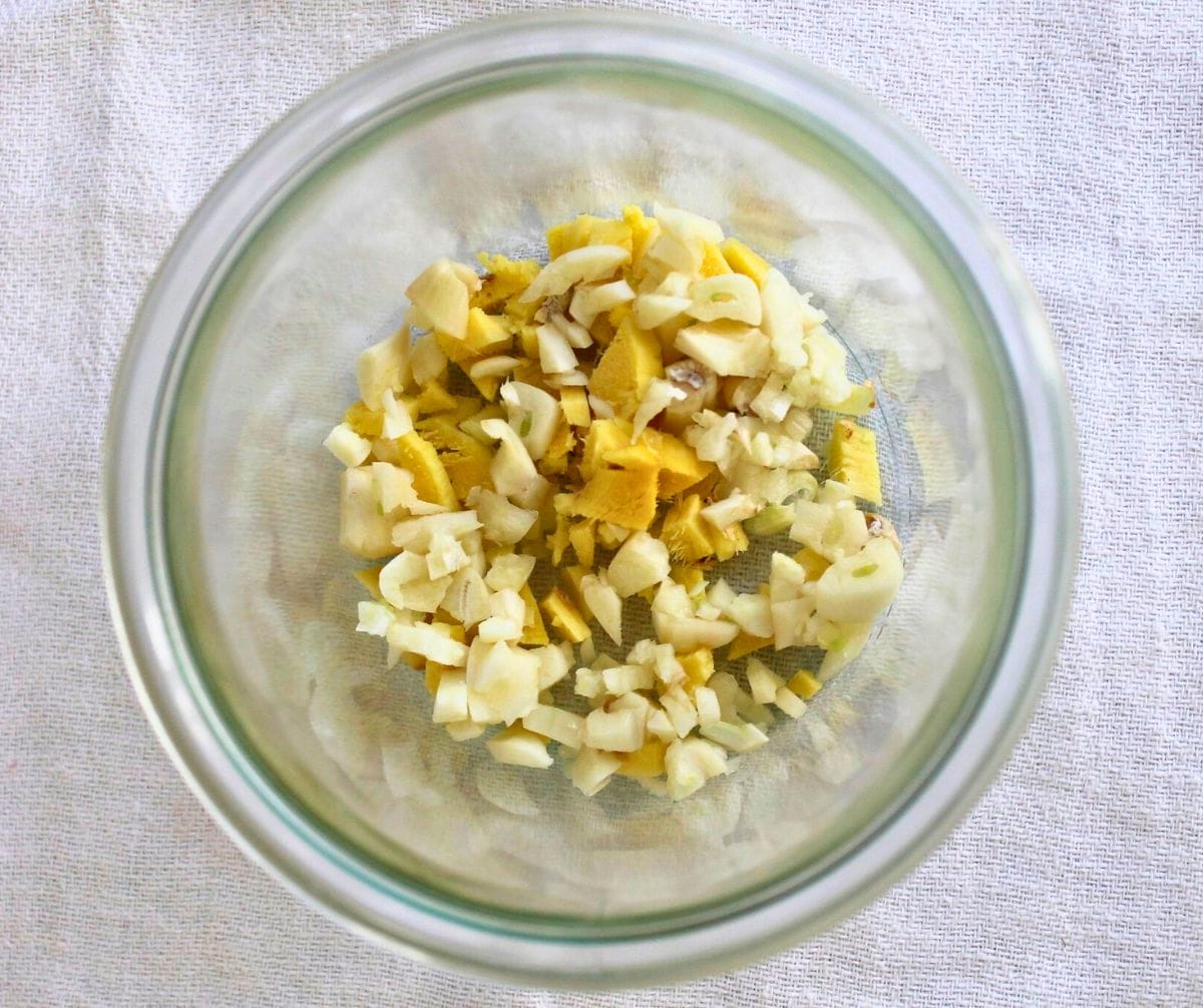 Chopped ginger root, horseradish root, garlic, and onion in a glass jar.