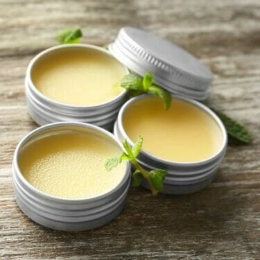 Three tins of all-purpose salve with peppermint sprigs.