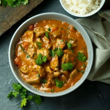 A bowl of curry chicken made with homemade masala and topped with cilantro.