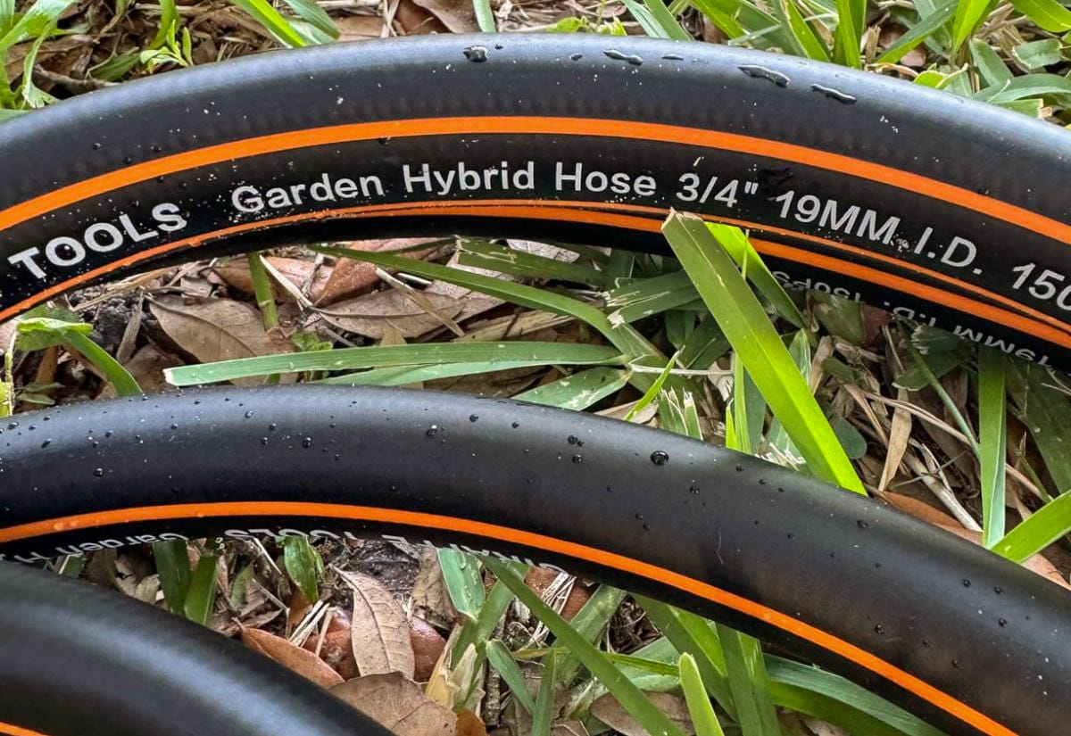Close-up of a black hybrid rubber and polymer garden hose labeled 3/4 inch, showing durable construction and flexible design for heavy use.