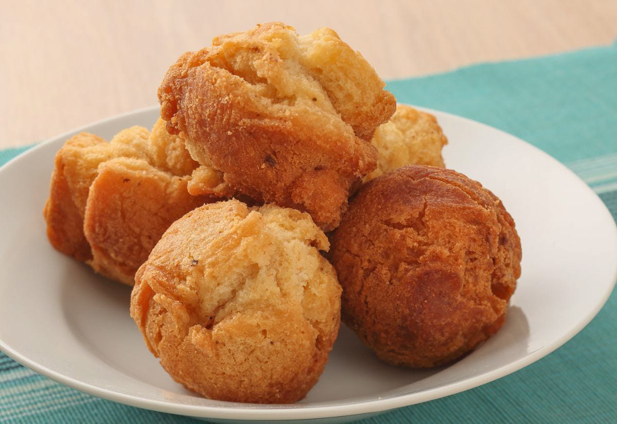 A plate stacked with golden-brown muffins made with spaghetti squash, showing their crisp edges and soft texture under warm indoor lighting.