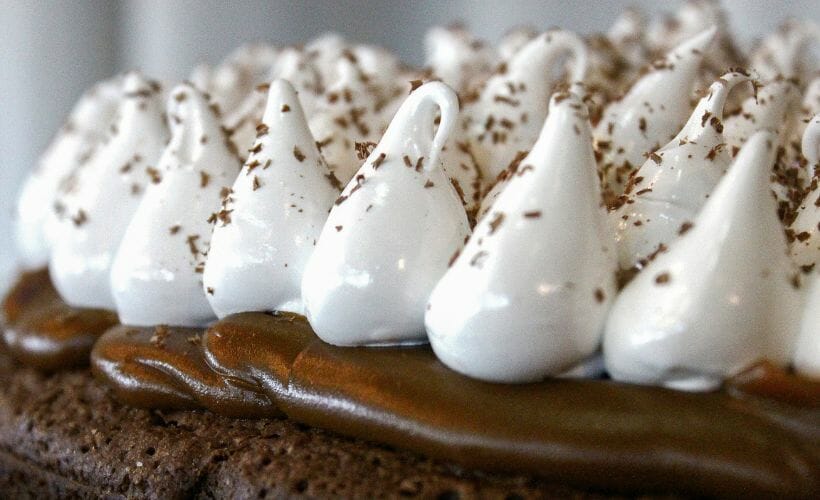 A closeup view of chocolate pie with whipped cream mounds and shaved chocolate.