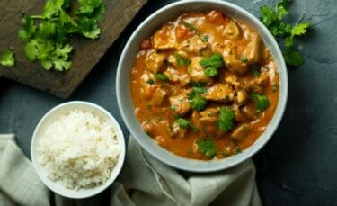 A close up of curry made with homemade masala and a small bowl of white rice.