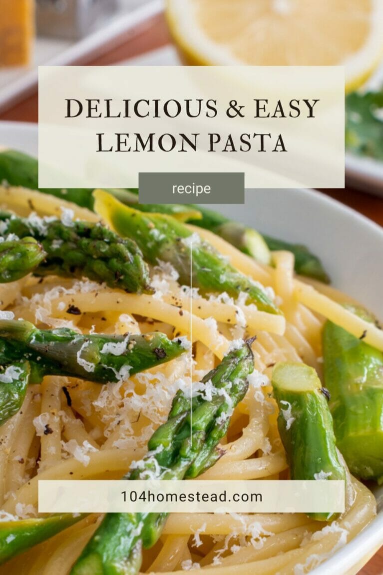 A closeup of a lemon pasta dish, in a white bowl, topped with asparagus and shredded parmesan cheese.