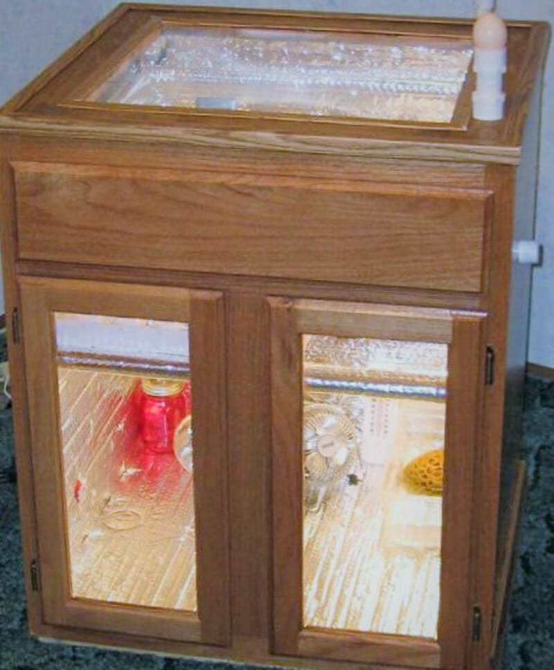 A chicken egg incubator made from an oak kitchen cabinet base unit.