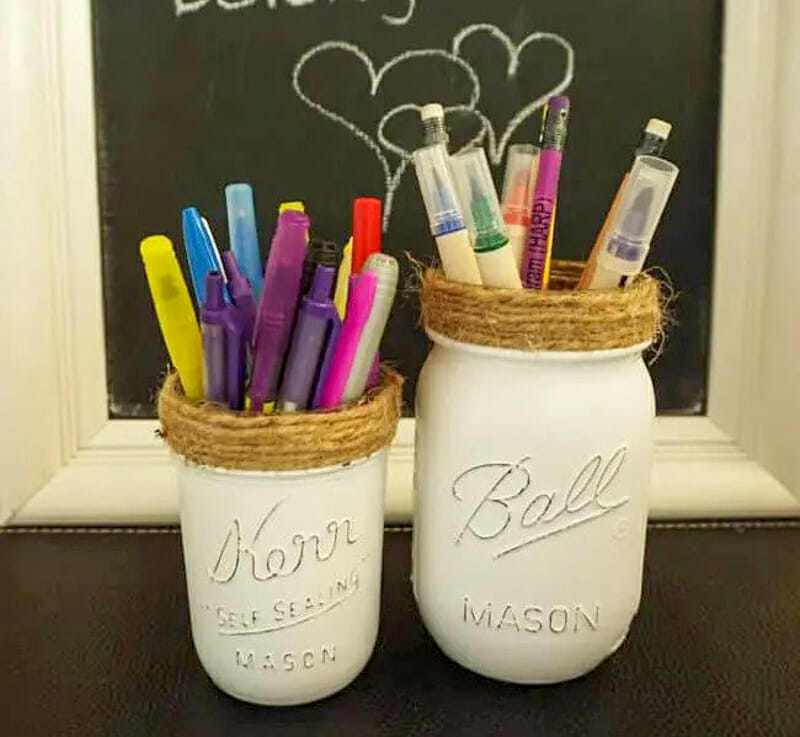 White painted mason jars with twine wrapped around the tops storing markers and pencils.
