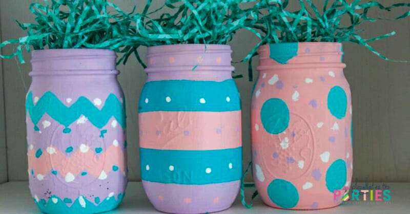 Mason jars painted to resemble Easter eggs with fake grass coming out of the tops.