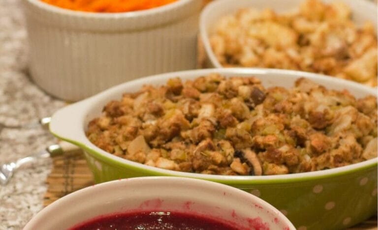 Close-up of baked stuffing and cranberry sauce in serving dishes on a kitchen counter, showcasing traditional Thanksgiving leftovers ready for reuse in slow cooker recipes.
