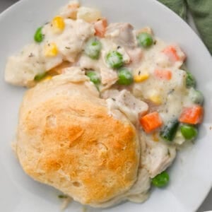 Creamy leftover turkey and vegetable casserole topped with a golden biscuit, served on a white plate—an easy slow cooker meal made from Thanksgiving leftovers.