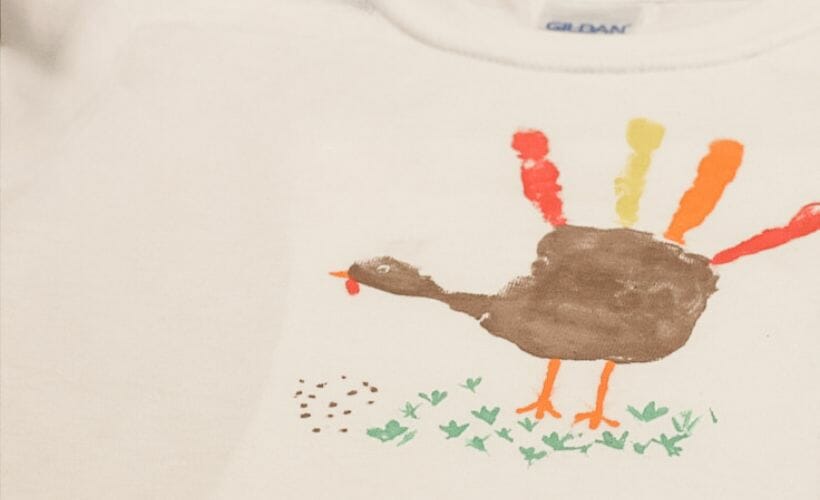 A handprint turkey on a white t-shirt.