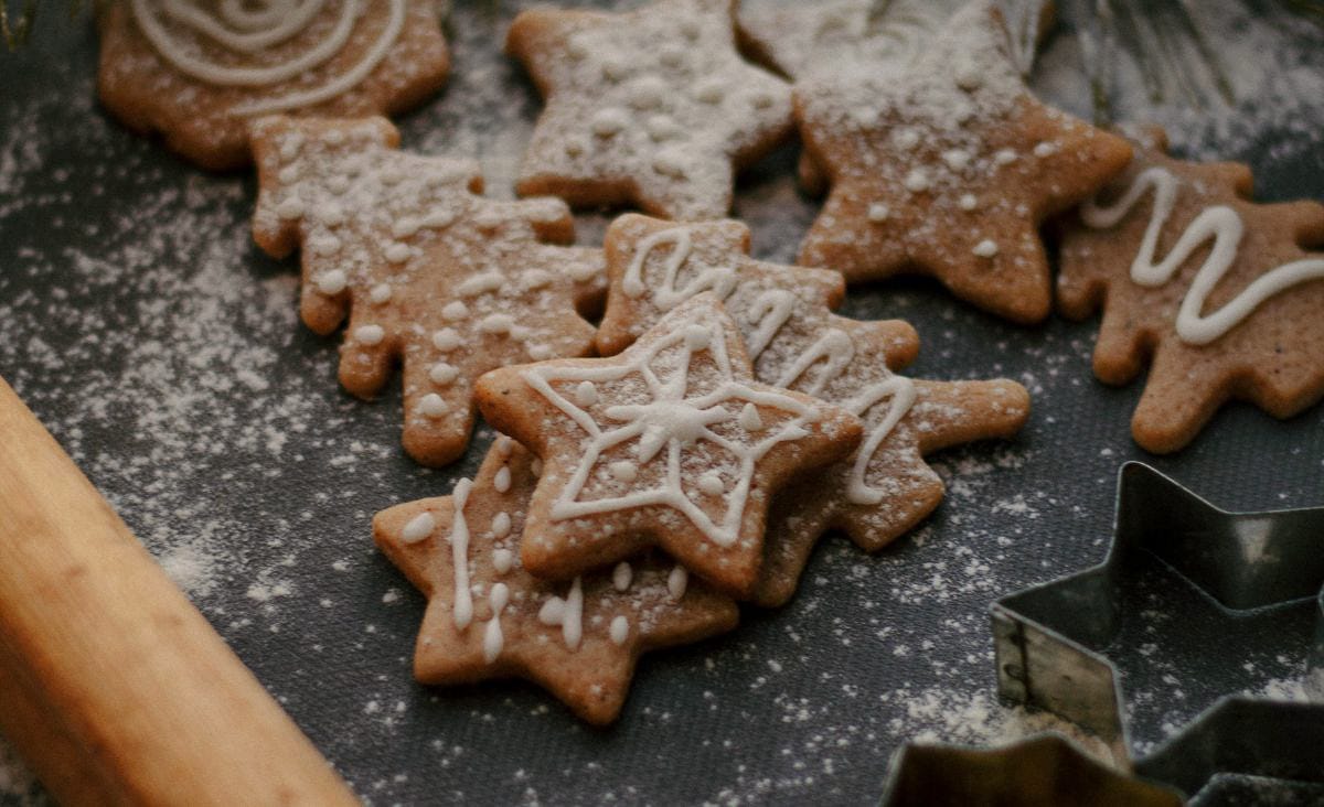 Close-up of simple iced gingerbread star cookies dusted lightly with powdered sugar on a dark baking mat.