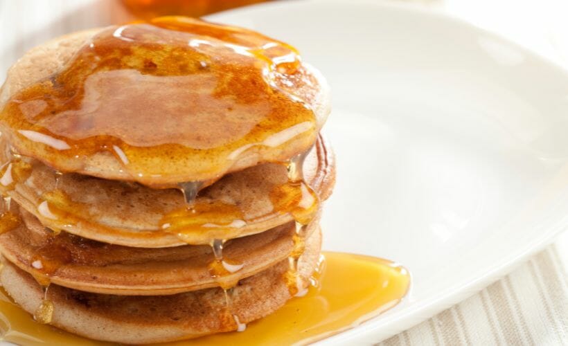 A stack of gingerbread pancakes covered in maple syrup.