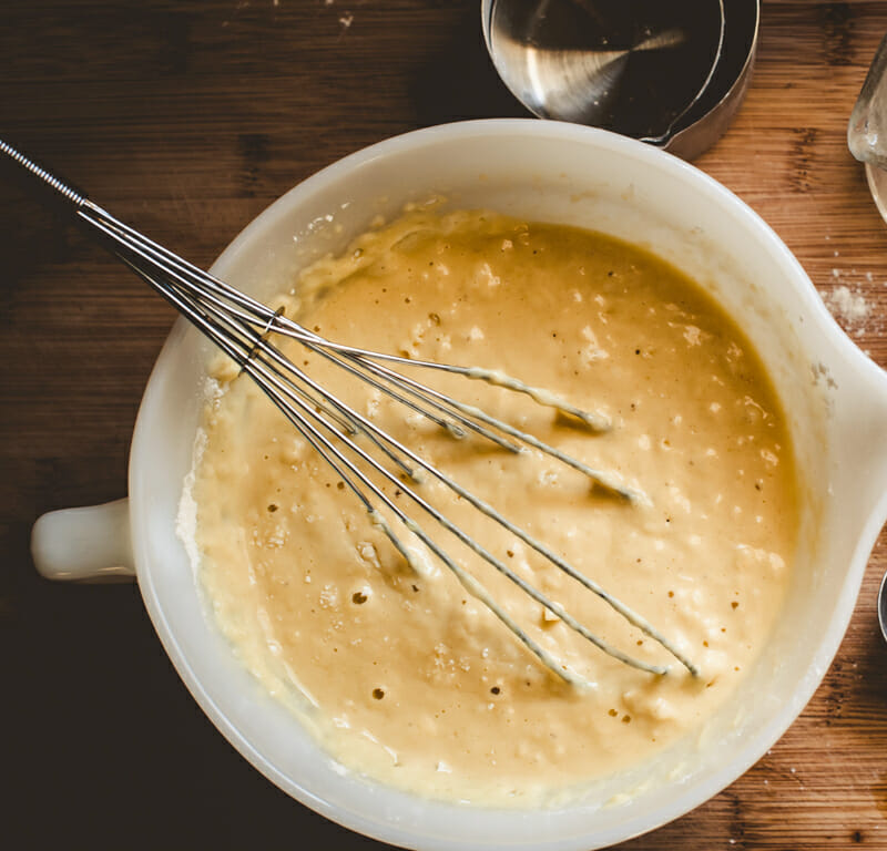 Mixing up gingerbread pancake batter with a whisk in a while bowl.