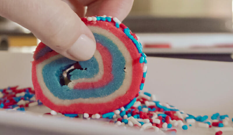 Rolling cookie disks in sprinkles.