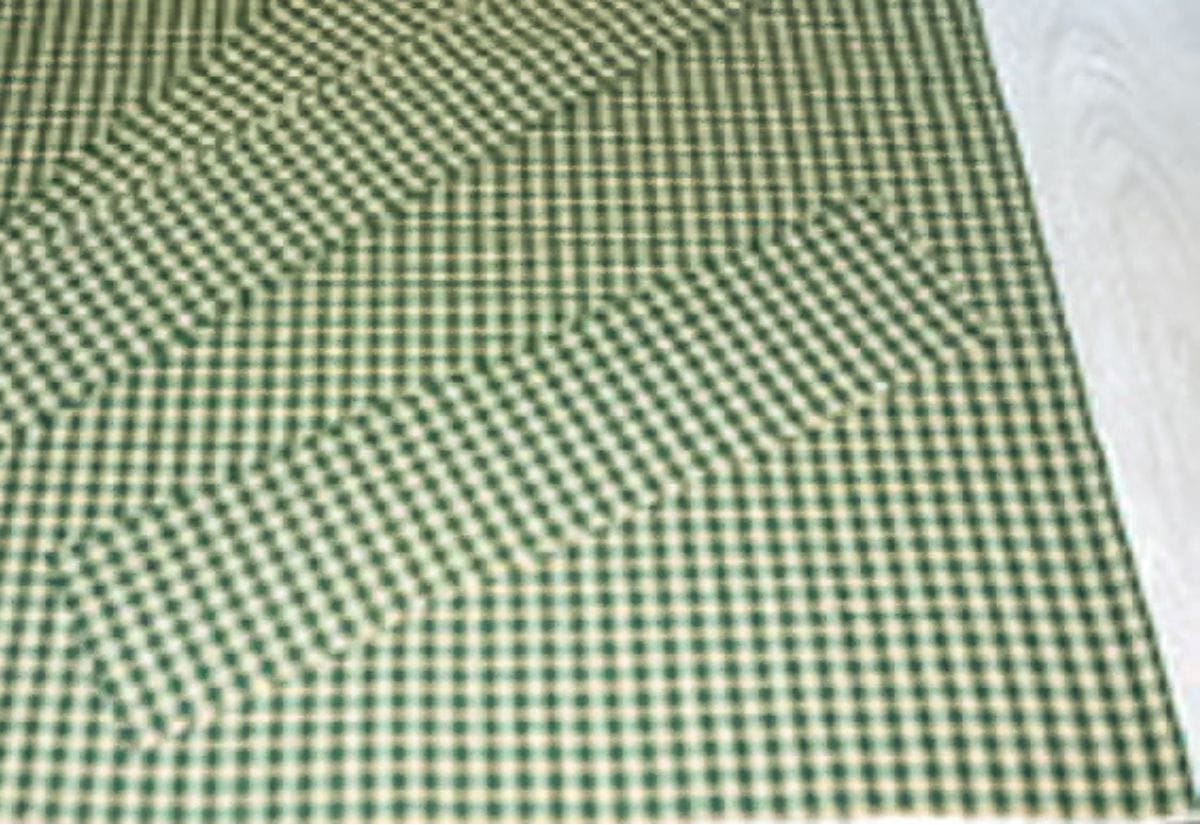 Green gingham fabric laid flat for cutting and sewing the body of the harvest apron.