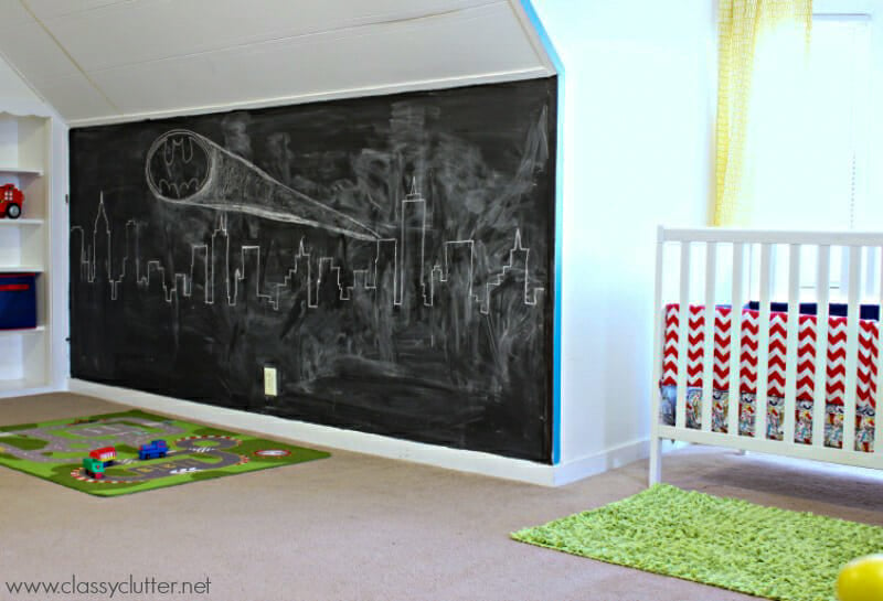 A wall painted in chalkboard with Gotham City and the Batman logo drawn on it with chalk.