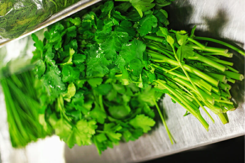 Fresh parsley stored in a bundle in the crisper drawer of the fridge.