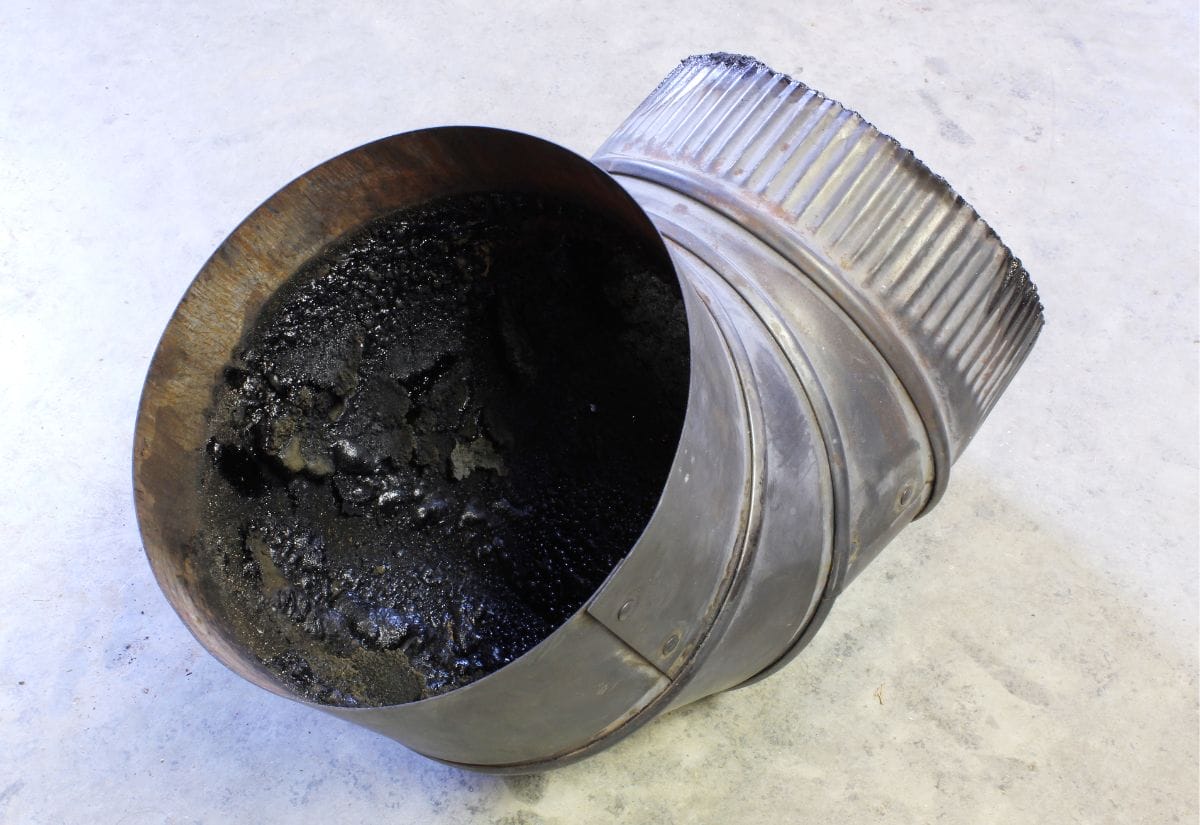 A metal chimney pipe showing heavy creosote buildup, highlighting the importance of regular cleaning and maintenance.