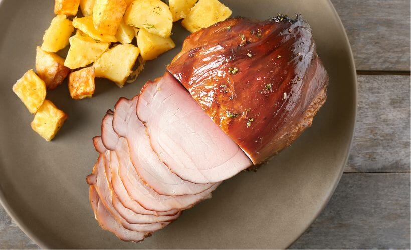 A platter of maple glazed ham and roasted potatoes.