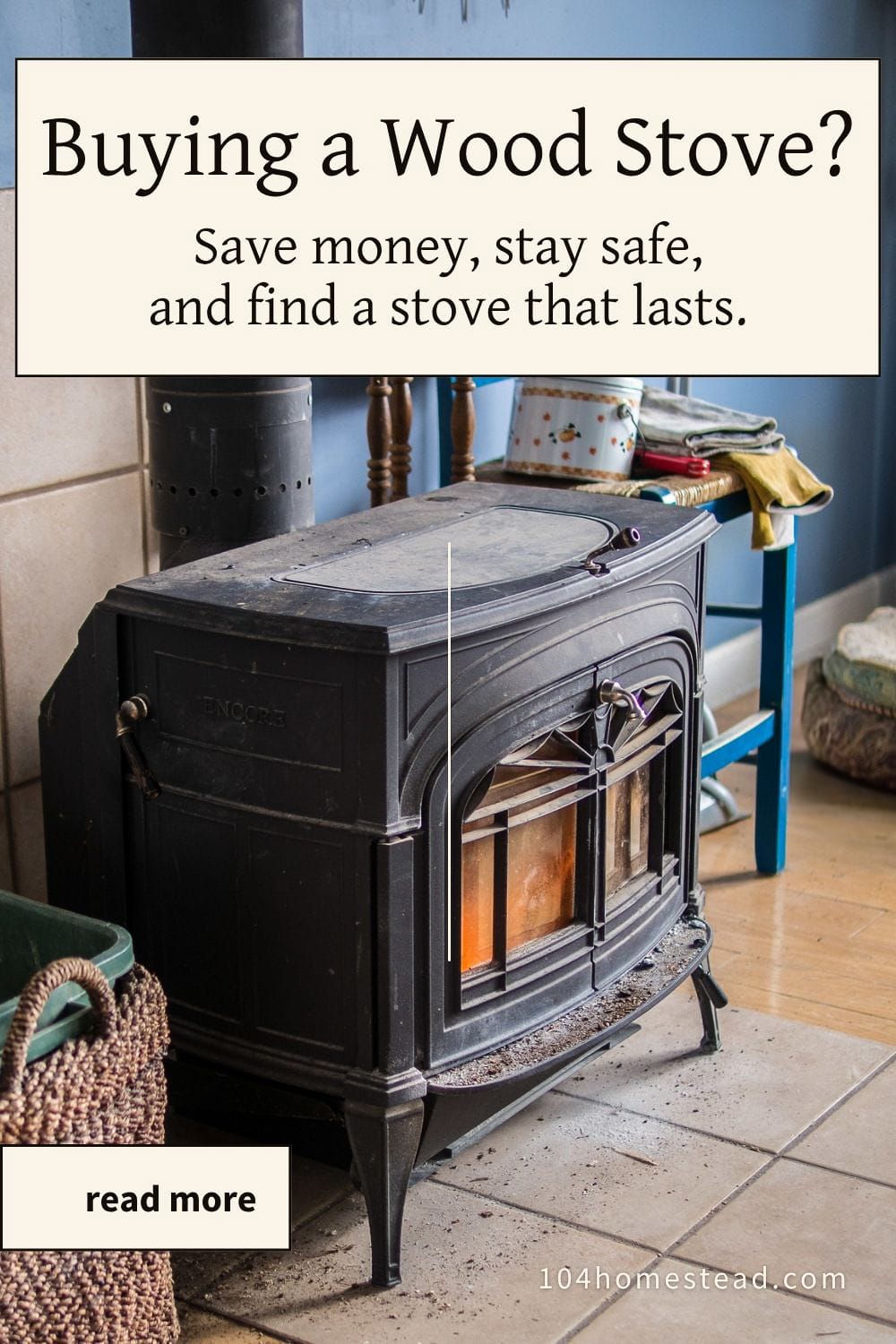 Black cast-iron wood stove burning warmly in a cozy farmhouse kitchen, with a woven basket of kindling nearby and a vintage blue chair in the background. Text overlay reads “Buying a Wood Stove? Save money, stay safe, and find a stove that lasts.”