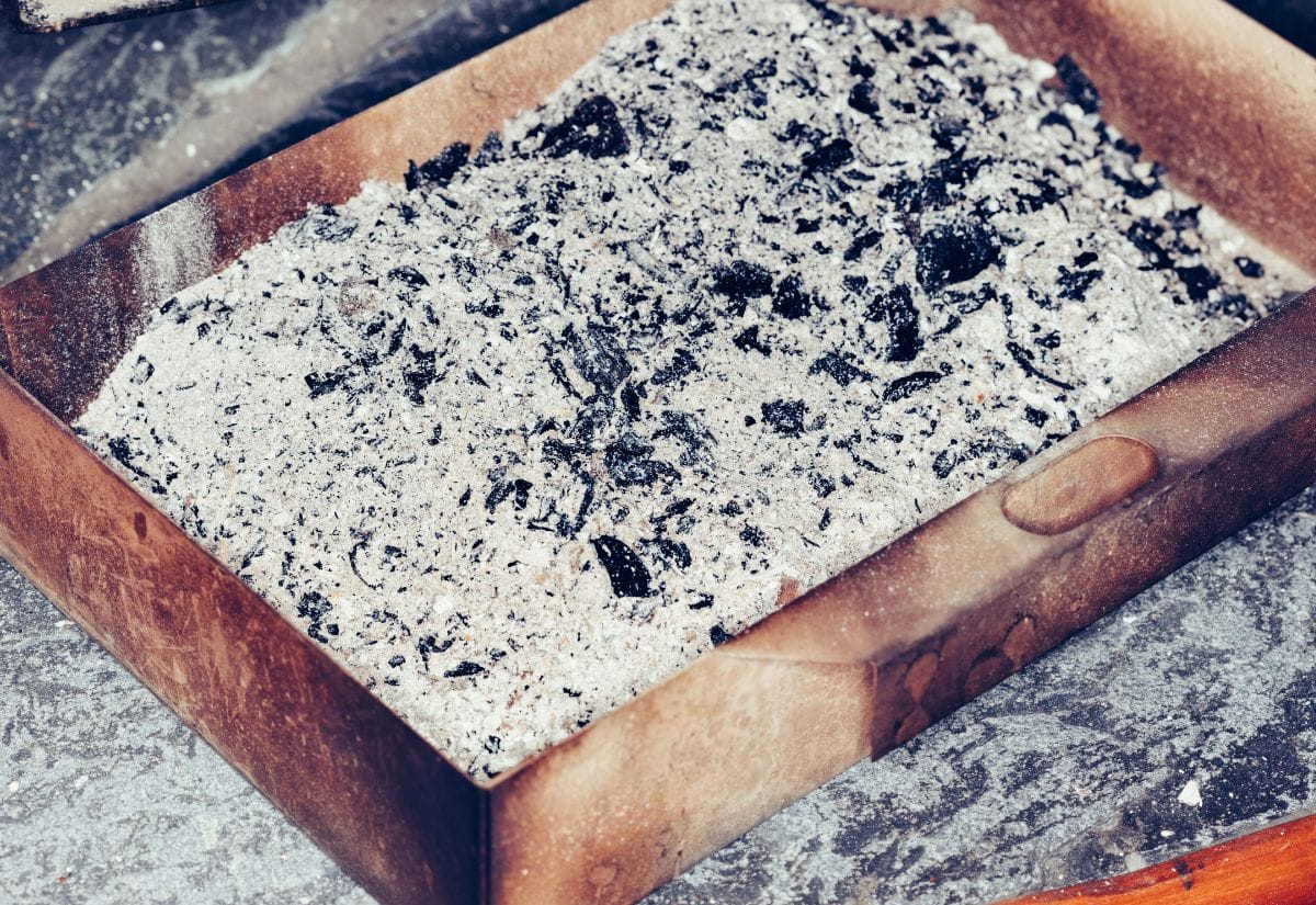 A tray filled with wood ash, a key component for cleaning wood stove glass naturally.