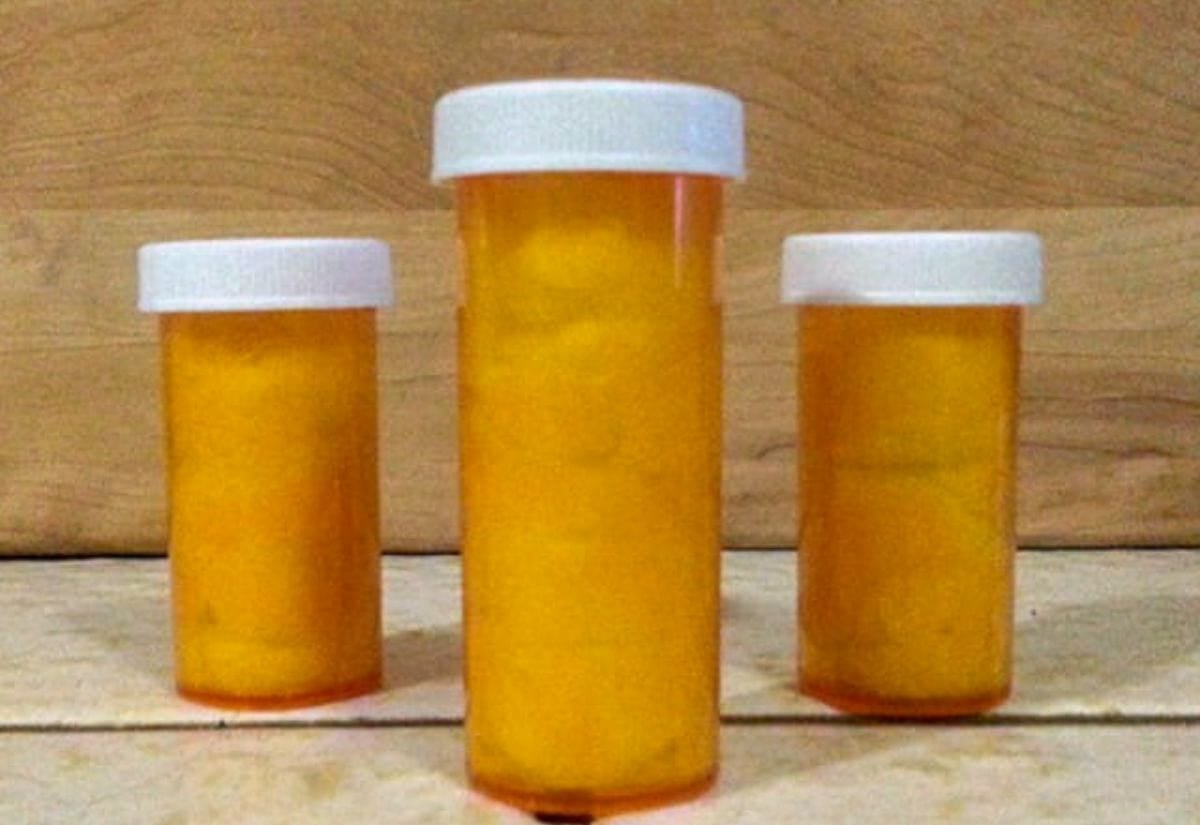 Three orange prescription pill bottles with white caps filled with cotton balls, ready to be used as DIY fire starters.