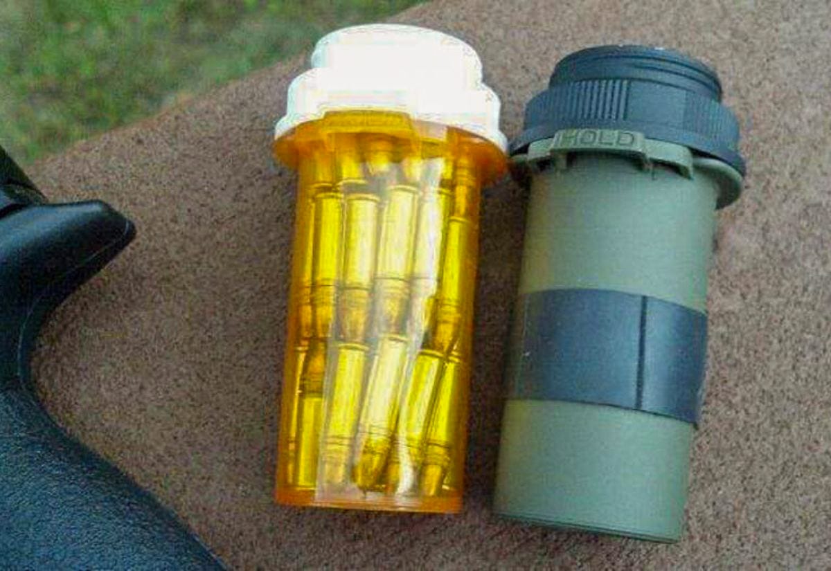 Prescription pill bottle filled with rifle ammunition, shown beside a green military-style container.