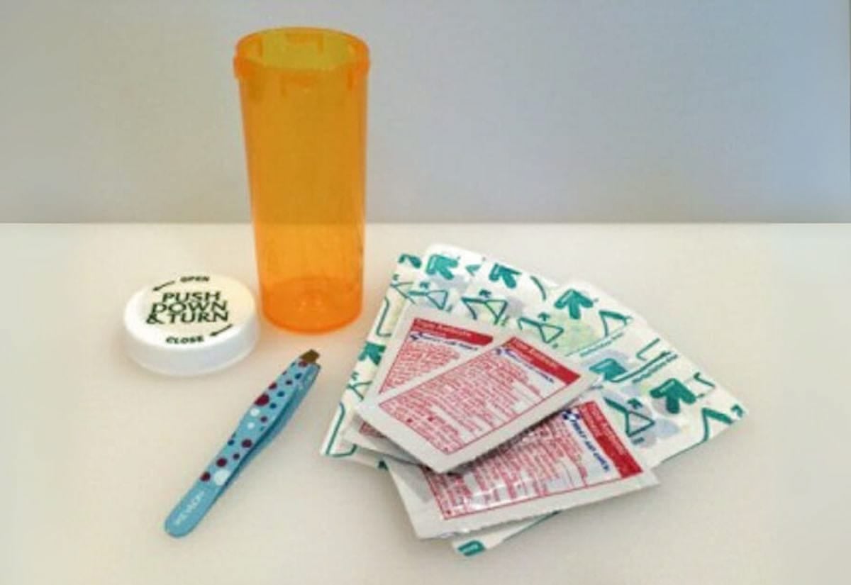 Empty pill bottle shown alongside tweezers and antiseptic wipes, ready to be assembled into a mini first aid kit.
