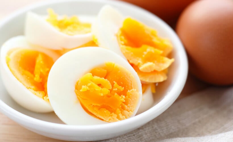 A white bowl of perfectly hard boiled chicken eggs.