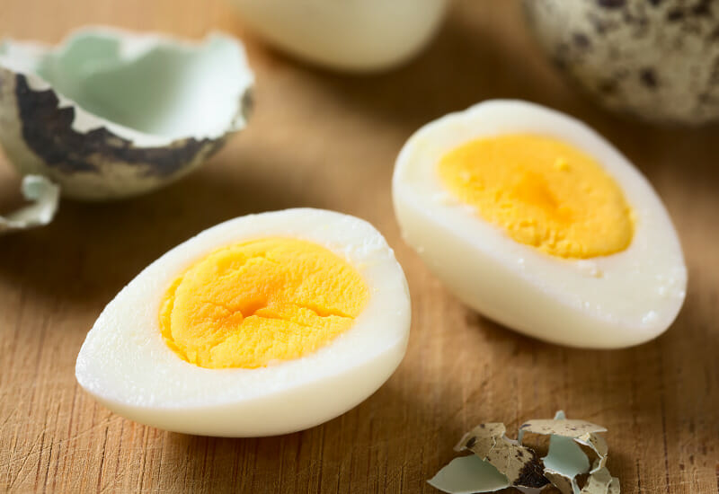 Hard boiled quail eggs on a wooden cutting board.