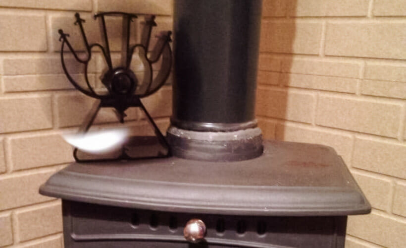 A heat-powered fan sitting on top of a wood stove.