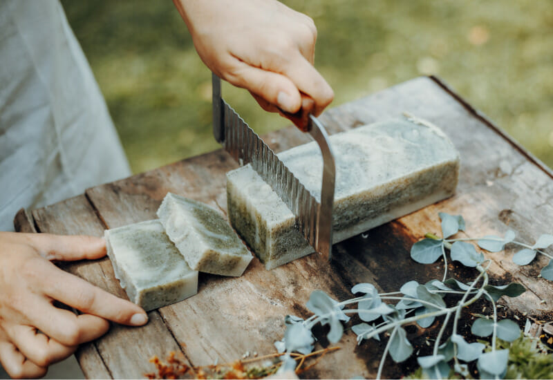 Cutting cold process soap on a wooden table.