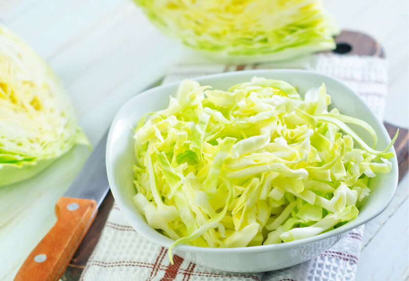 Finely chopped white cabbage in a white bowl.