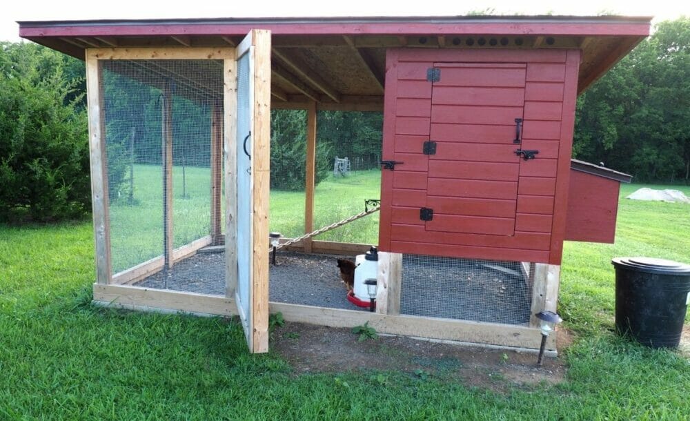 A dark red elevated chicken coop with attached run.
