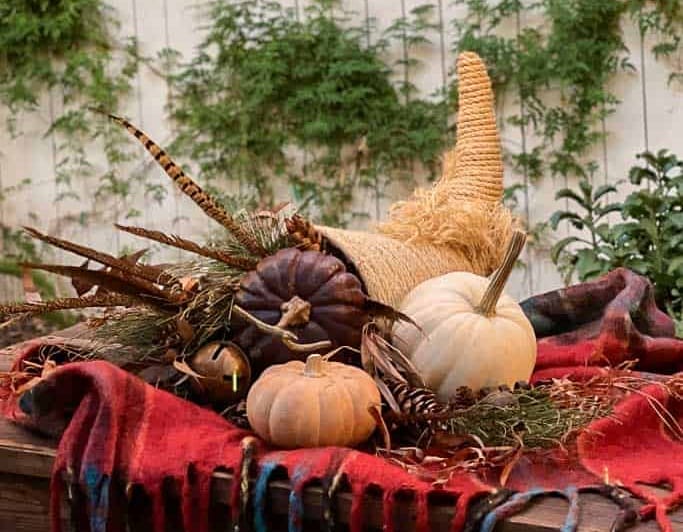 A cornucopia made of rope and filled with pumpkins, gourds, pine cones, and dried herbs.