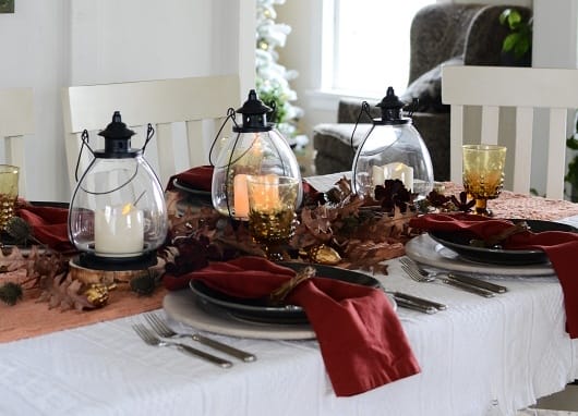 Antique lanterns with battery powered candles, surrounded by leaves and twigs.